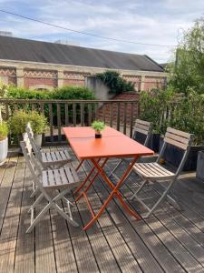 a red table and two chairs on a deck at Agréable et Spacieuse maison centre ville Saint-Omer in Saint-Omer