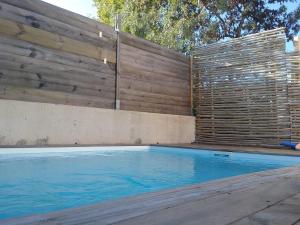 a swimming pool in front of a wooden fence at Villa Rose Suite et chambres in Montpellier