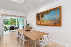 uma sala de jantar com uma mesa de madeira e cadeiras em Seascape Holidays Villas on Murphy Street em Port Douglas