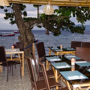 a restaurant with tables and chairs on the beach at Blue Lagoon Guest house for Backpakers in Puerto Galera