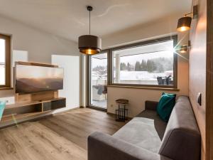 sala de estar con sofá y TV de pantalla plana en Ledermaier Loft & Lodge`s eU, en Achenkirch