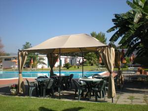 a table and chairs under an umbrella next to a pool at Villaggio Artemide in Giardini Naxos