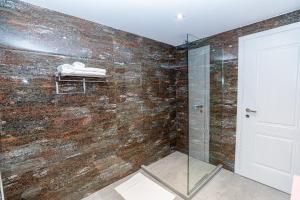 baño con ducha a ras de suelo junto a una pared de piedra en Hakuna Matata Residence & Apartments, en Vlorë