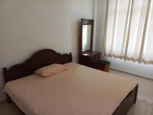 a bedroom with a bed with a wooden headboard and a mirror at The Anchorage Villa - Negombo in Negombo