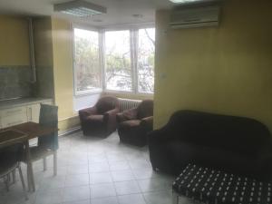 een woonkamer met stoelen en een tafel en ramen bij Kalamaras Apartments in Skopje