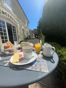 a table with cups and plates of food on it at Logis Domaine du Prieuré in Tonnay-Boutonne