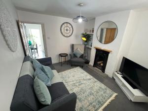 a living room with a black couch and a fireplace at Central Cottage, Hot Tub in Shottery