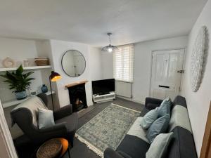 Central Cottage, Hot Tub في Shottery: غرفة معيشة مع أريكة ومدفأة
