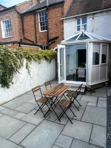 a patio with chairs and a table and a greenhouse at Central Cottage, Hot Tub in Shottery