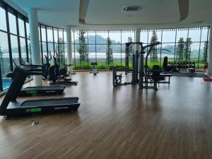 een fitnessruimte met loopbanden en fitnessapparatuur in een kamer met ramen bij Alpine Parkland Netflix 5 beds at MRT Batu 11 Cheras in Cheras