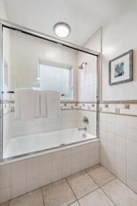 a white bathroom with a tub and a window at Villa Lanai at the Sunset Cove Villas in Laguna Beach