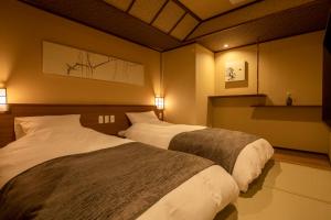 Jozankei Onsen Yurakusoan في Jozankei: سريرين في غرفة الفندق مع إضاءة
