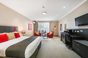 Habitación de hotel con cama grande y escritorio. en Platinum International en Toowoomba