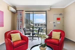 una sala de estar con 2 sillas rojas y una mesa. en Platinum International en Toowoomba