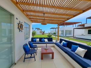 un patio con sofás azules y una pérgola de madera en Alquilo casa de playa Condominio Playa Azul cerca de Asia, en Cerro Azul