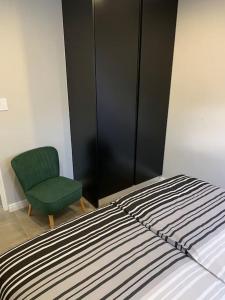 a bedroom with a bed and a green chair at Maîté Iphupho in Somerset West