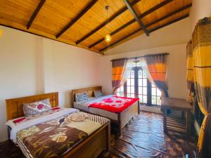 1 dormitorio con 2 camas y ventana en travellers nest inn en Nuwara Eliya