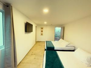 a room with two beds and a flat screen tv at Hotel Campestre Villa Mary in Santa Rosa de Cabal