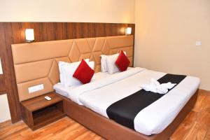 Hotel Bhagyaraj Palace - Best Hotel In Kanpur في كانبور: غرفة نوم بسرير كبير ومخدات حمراء