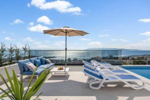 a group of lounge chairs and an umbrella on a patio at Luxury Villa Sagnia, 4 en-suite bedrooms, sea views in Makarska
