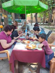 un grupo de personas sentadas en una mesa comiendo comida en Wild Horizons Guest House, en Sauraha