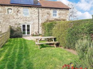 a wooden picnic table in front of a stone house at Cheviot View in Beal