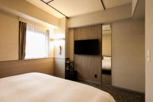 神戸市にあるSK HOTEL 神戸駅前のベッドと大きな鏡が備わるホテルルームです。