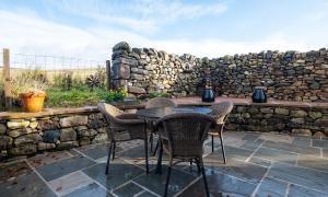 a table and chairs on a patio with a stone wall at Sherriff in Penrith