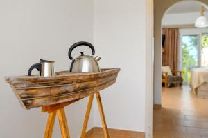 un bollitore per tè metallico su un supporto in legno in una stanza di Afroditi Superior Apartments a Archangelos