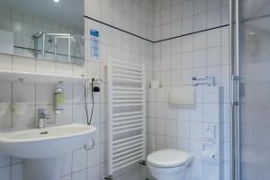 a white bathroom with a toilet and a sink at Hotel Ekke Nekkepenn in Nebel
