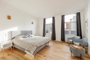 biała sypialnia z dużym łóżkiem i oknami w obiekcie SurPRIMO - Gerenoveerd appartement w Antwerpii