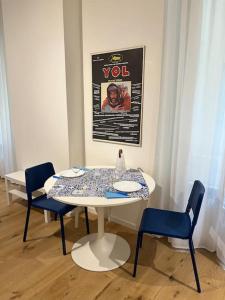 un tavolo bianco con sedie blu e una foto sul muro di Monolocale nel cuore di Genova a Genova