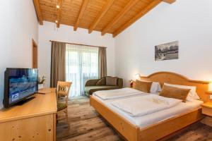 a bedroom with a bed and a tv and a couch at Berggasthof Hinterreit in Maria Alm am Steinernen Meer