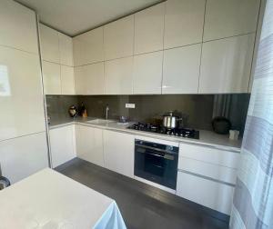 uma cozinha com armários brancos e um forno com placa de fogão em Villa I tre Cipressi em Lido di Camaiore