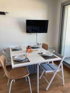 a white table with chairs and a tv on a wall at Studio Cabine Pornichet Vue Mer 4 pers in Pornichet