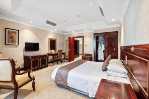 Cette chambre comprend un lit, un bureau et une télévision. dans l'établissement Chairmen Hotel, à Doha