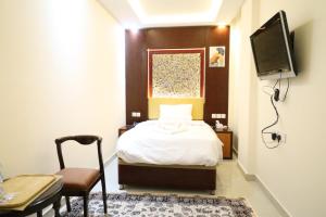 a bedroom with a bed and a tv and a chair at Tribes hotel in Sohar