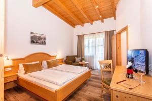 a bedroom with a bed and a desk with a computer at Berggasthof Hinterreit in Maria Alm am Steinernen Meer