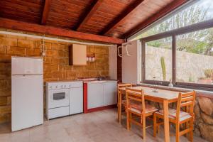 een keuken met witte apparatuur en een tafel met stoelen bij Villa Salvo in Pachino