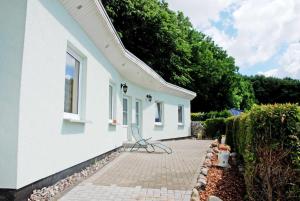 una casa blanca con un banco en un patio de ladrillo en Ferienwohnung Patzig auf Rügen, en Patzig