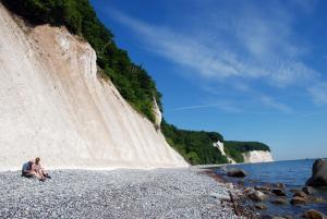 un hombre sentado en una playa rocosa junto a un acantilado en Ferienwohnung Patzig auf Rügen, en Patzig