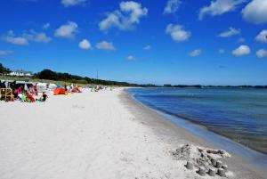 a beach with people sitting on the sand and the water at Ferienwohnung Patzig auf Rügen in Patzig