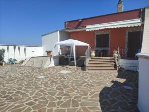 eine Terrasse mit einem weißen Zelt und einem roten Gebäude in der Unterkunft B&B Le Cave in Avetrana