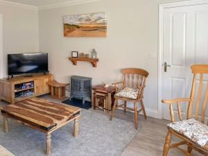 a living room with a tv and wooden furniture at Lapwing Lodge in New Hunstanton