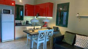 een keuken met rode kasten en een tafel en stoelen bij Katarina Apartments in Kefallonia