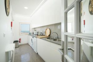a white kitchen with a sink and a window at Costa Beach Apartment by The Portuguese Butler in Costa da Caparica