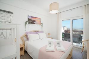 a white bedroom with a bed and a window at Costa Beach Apartment by The Portuguese Butler in Costa da Caparica