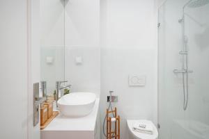 a white bathroom with a sink and a toilet at Costa Beach Apartment by The Portuguese Butler in Costa da Caparica