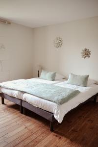 uma cama grande num quarto branco com pisos em madeira em Château de La Vallade em Saint-Porchaire