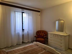 1 dormitorio con vestidor, TV y silla en Appartamento con giardino, en Pomarance